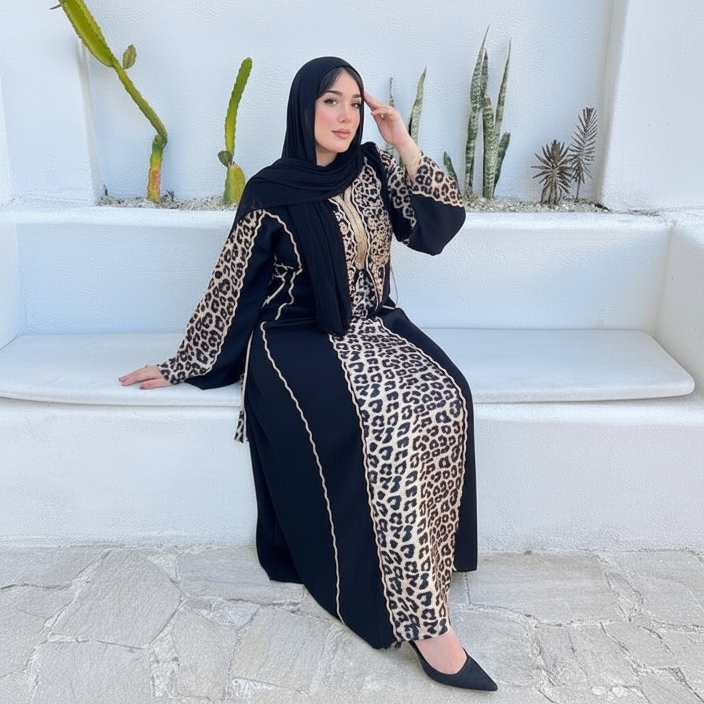 Woman wearing a black abaya with leopard print details sitting on white steps.