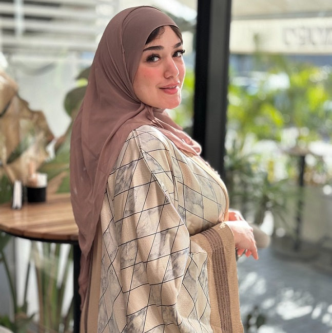 Woman wearing a hijab and patterned outfit in an outdoor setting