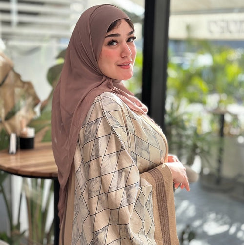 Woman wearing a hijab and patterned outfit in an outdoor setting