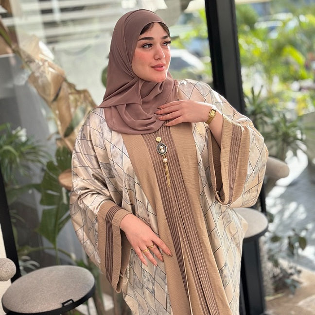 Woman wearing a beige and brown traditional outfit with a hijab indoors.