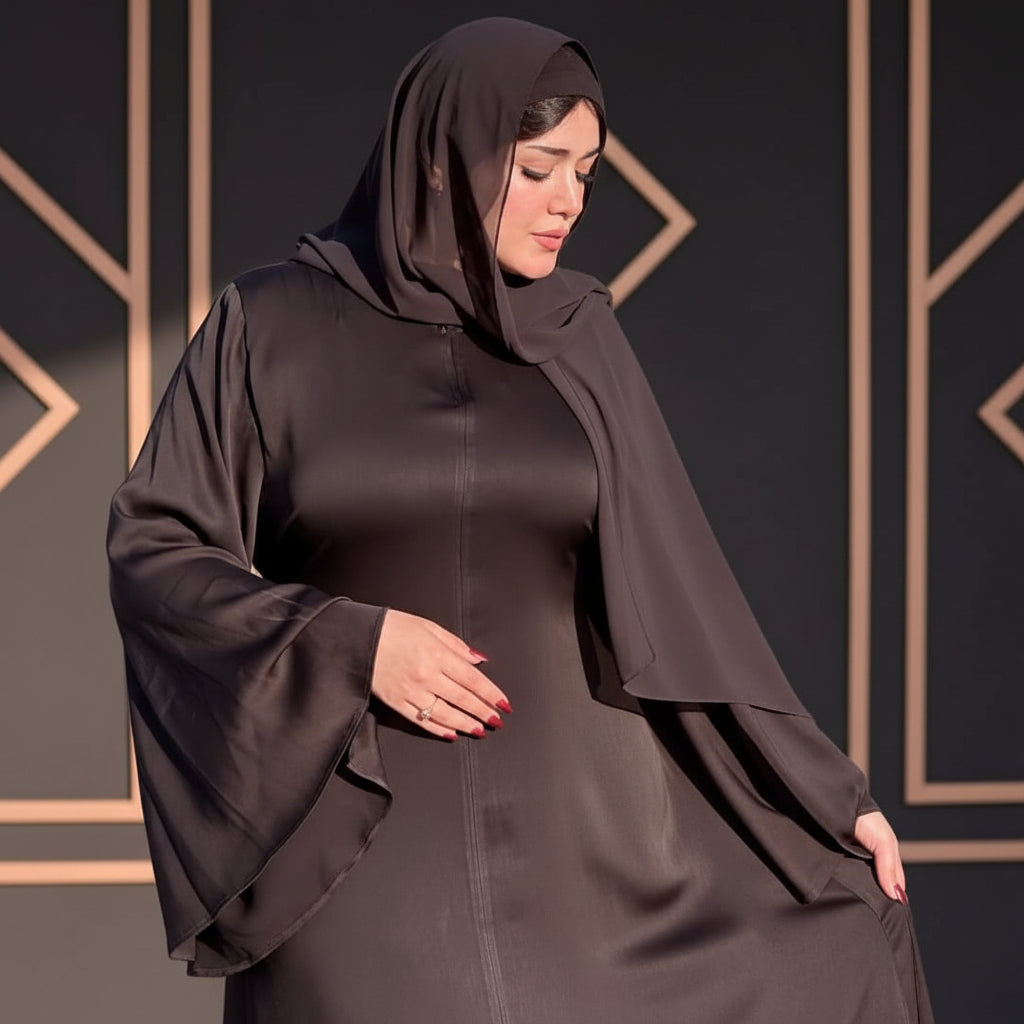 Woman wearing a dark brown abaya in an outdoor setting.